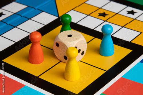 four multi-colored playing figures in their places of the playing board, in the middle there are wooden dice