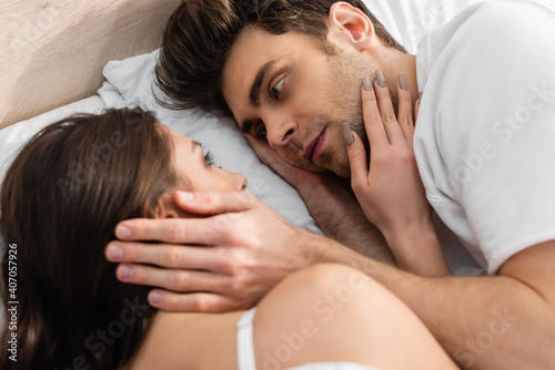 top view of man and woman lying in bed and looking at each other