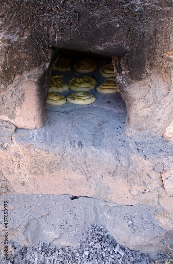 Obraz premium Ashes in front of a traditional wood oven made of a special kind of stone. Homemade breads are baked in the wood-fired oven. Selective focus.