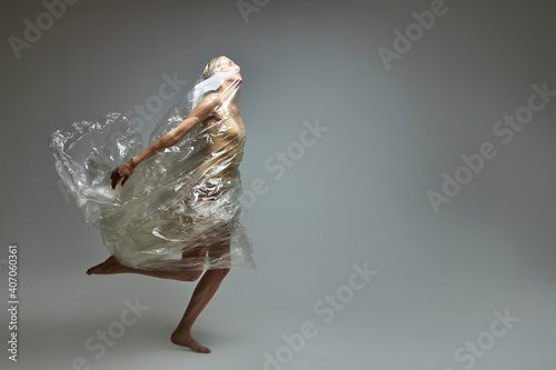 Fototapeta Naklejka Na Ścianę i Meble -  side view on female in a plastic bag, breaking free from plastic trash, showing the concept of irresponsibility of people to nature and the environment
