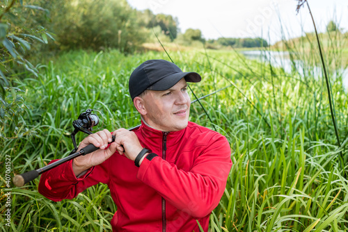 Portrait of a fisherman with a spinning. Guy with a fishing rod outdoors.