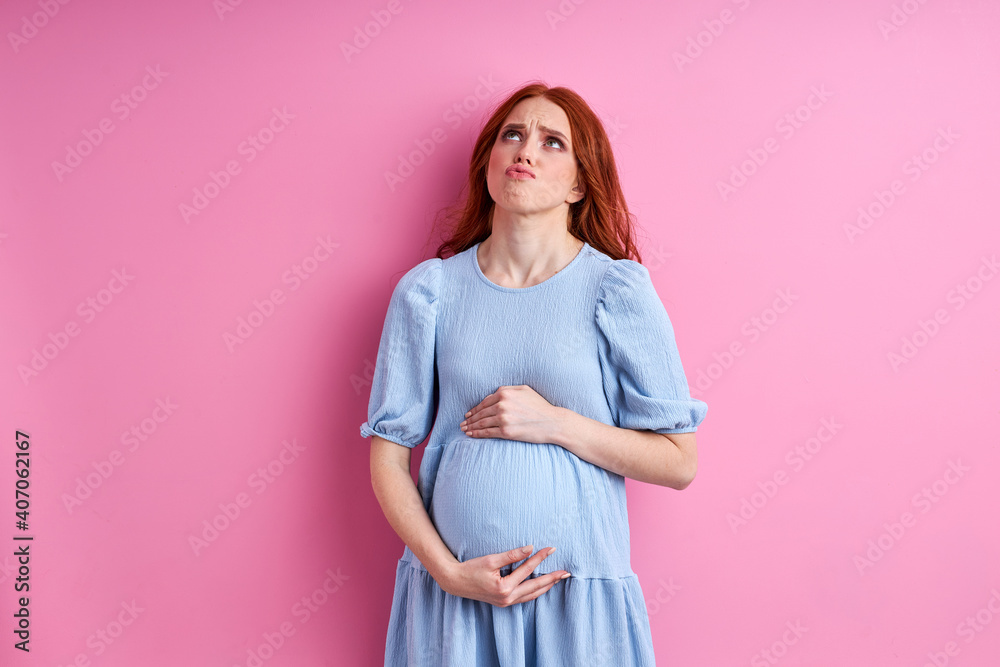 woman is tired to be pregnant, young female in blue dress stand posing isolated on pink background woman is tired to be pregnant, young female in blue dress stand posing isolated on pink background