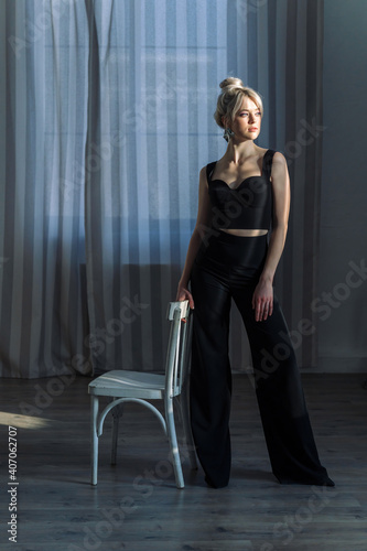 Studio portrait of a pretty blonde woman in black top and black pants, looking to the side. Blue eyes, young and tender-2.