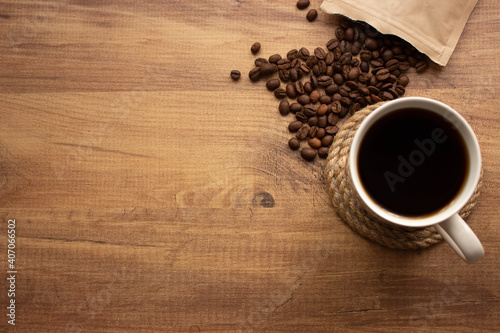 cup of coffee with beans on wooden table. For coffee background top view. Copy for your text.