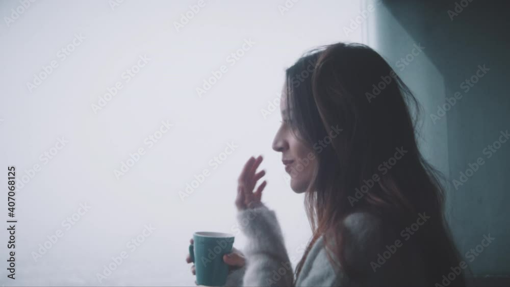 Young woman drinking coffe and watching outside her terrace