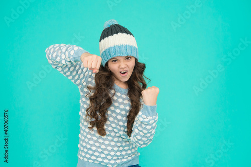 angry kid girl punching and warming up in winter knitted hat and sweater, anger