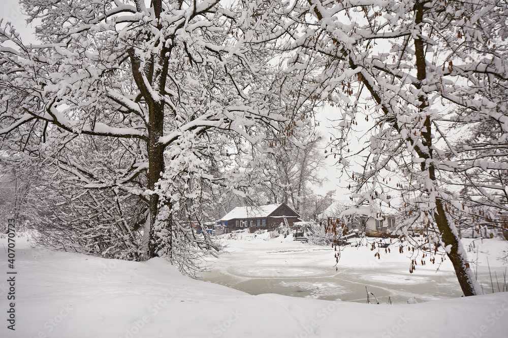 Winter rural scene. House near frozen lake. Hut on January lakeside.