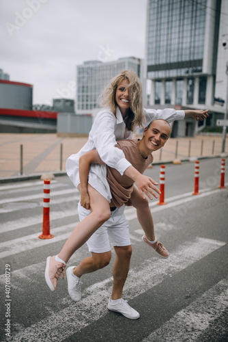  Man carrying young attractive woman on shoulders while spending time together outdoors in the city.Playful couple. © Igor