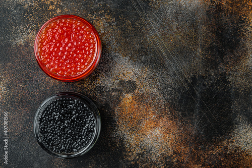 Glass jars with black and red caviar, on old dark rustic background, top view flat lay with copy space for text