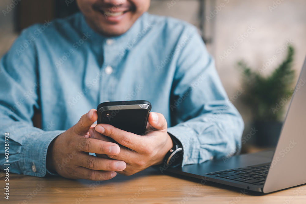 Entrepreneur Sitting at His Desk Works, Using Smartphone, Uses Social Media App, Emailing Business Partners, Messaging, Searching data and info. Entrepreneur Sitting at His Desk Works, Using Smartphone, Uses Social Media App, Emailing Business Partners, Messaging, Searching data and info.