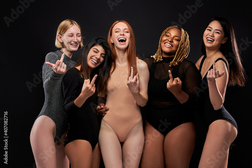 Fotografie women show fuck gesture at camera, multi-ethnic group of models in bodysuits iso