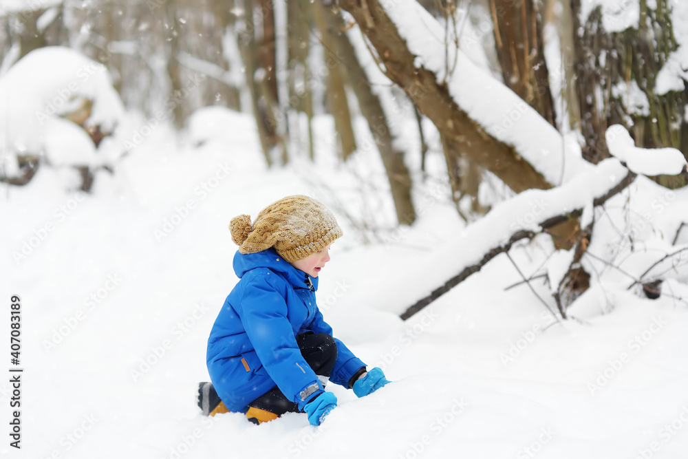 Little boy having fun playing with fresh snow. Active outdoors leisure for child in snowy winter day.