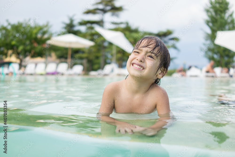 Cute little boy kid child splashing in swimming pool having fun leisure activity