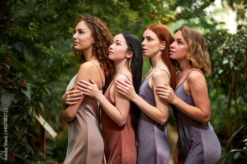 female models stand behind each other in contemplation of nature around, gorgeous ladies in silk wear posing, diverse natural beauty © Roman
