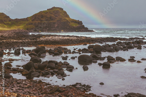 Rainbow over a rocky volcanic beach after a storm has passed by and atmosphere is still dark and moody. Iceland photo