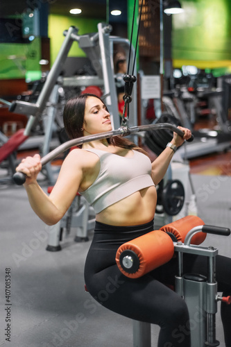 Young sportswoman exercising on lat machine in gym. High quality photo © herraez