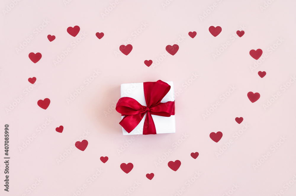 Romantic greeting card with red confetti hearts and a gift on a pink background. Valentines day, mothers day, birthday concept. Top view, flat lay.