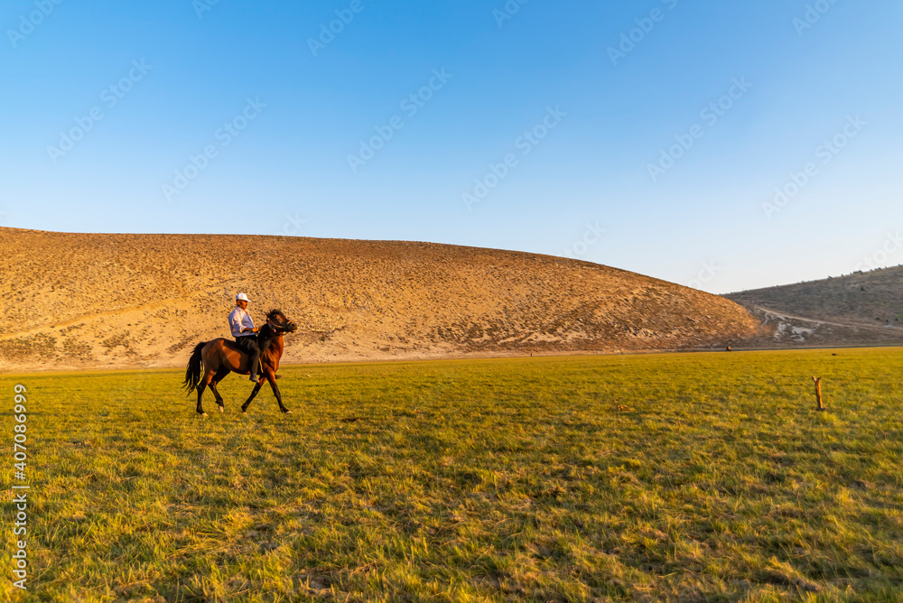 A wear a cap riding a red horse green valley under the sun light