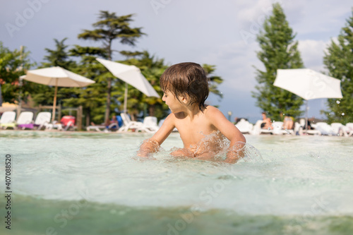 Cute little boy kid child splashing in swimming pool having fun leisure activity