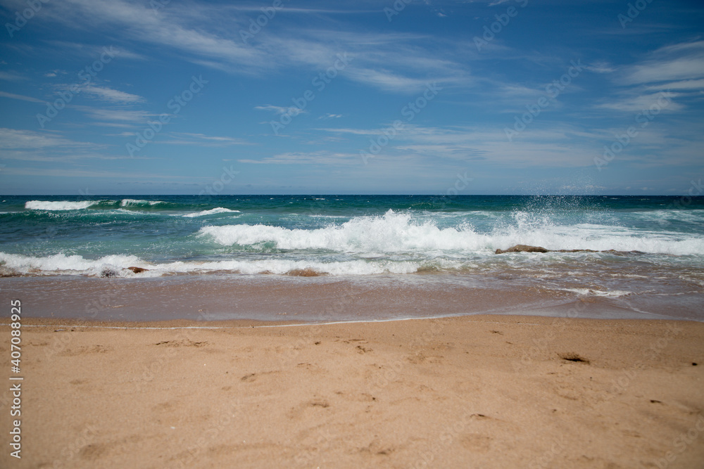 Beautiful sandy ocean beach with large rocks on the shore and in the water