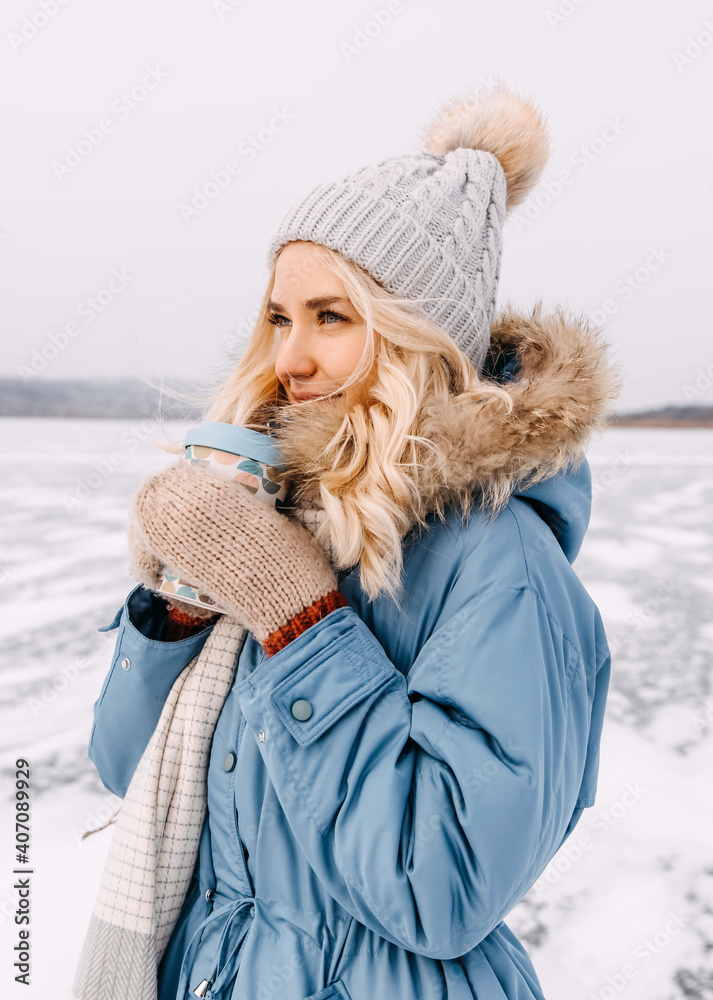 Young woman holding a reusable cup of coffee on winter day, outdoors. Young woman holding a reusable cup of coffee on winter day, outdoors.