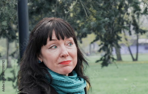 Portrait of a middle aged 45 year old brunette woman standing against the background of the park
