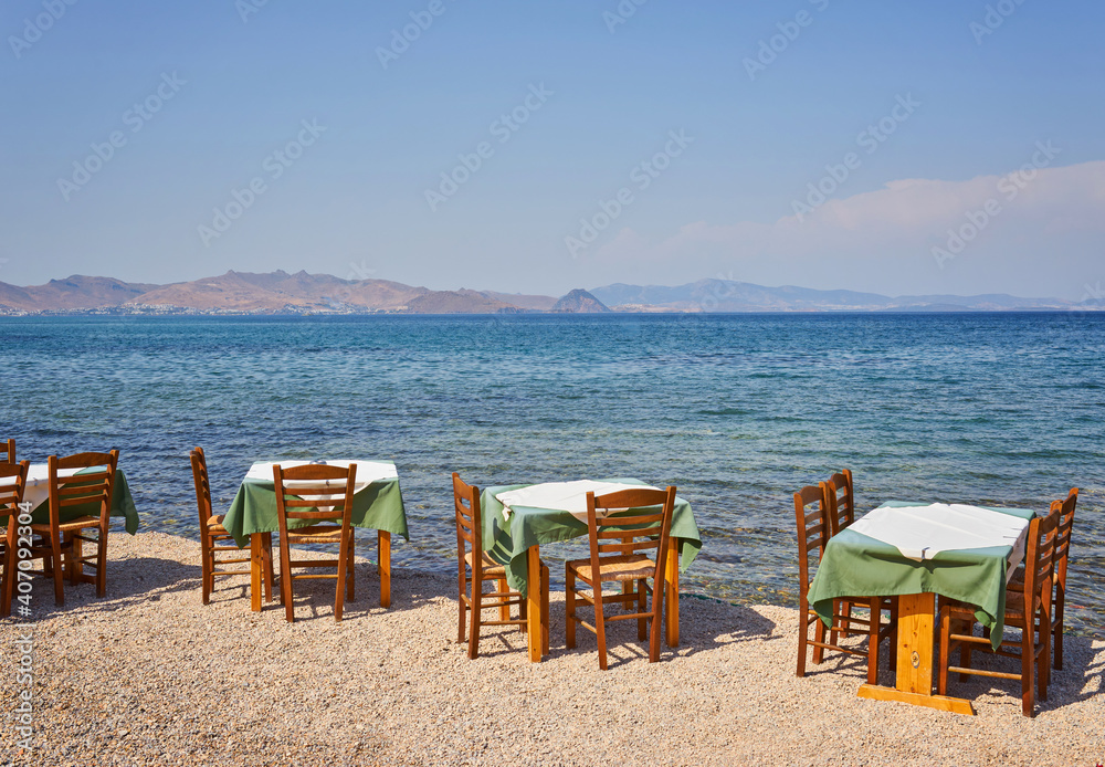 Greek beach with traditional blue tables and chairs