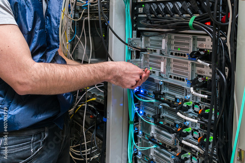 Technical work in the data center server room. Maintenance of computer equipment on the hosting site. There is a close-up of the switching of Internet communication wires.