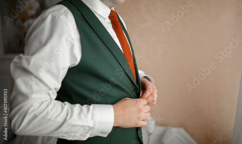 The man buttons up his vest.