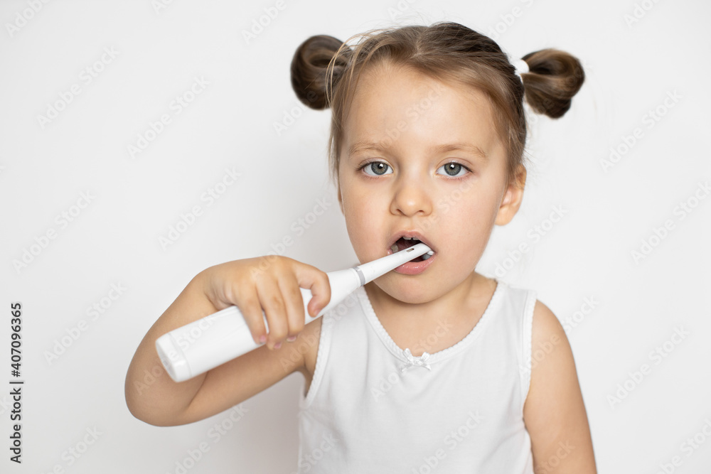 The concept of daily care and hygiene of the oral cavity, prevention of dental caries. Adorable little 3 years old kid girl in the morning cleans the teeth with modern electric toothbrush. The concept of daily care and hygiene of the oral cavity, prevention of dental caries. Adorable little 3 years old kid girl in the morning cleans the teeth with modern electric toothbrush.