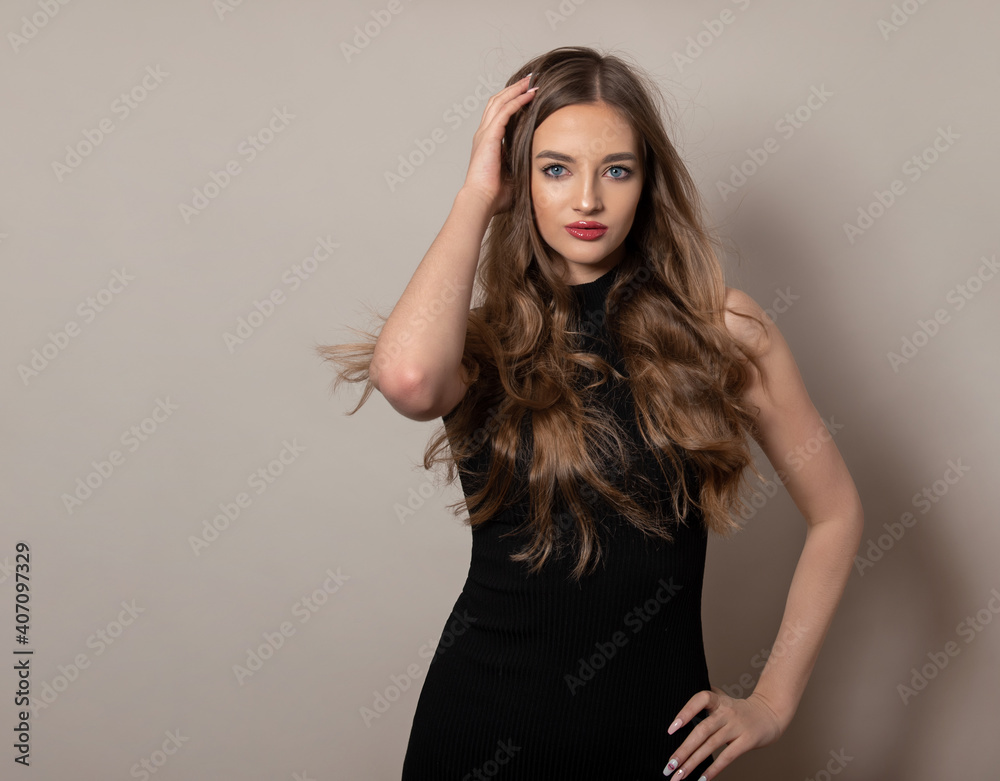 Beautiful young woman with long shiny and healthy hair posing in dress on grey background Beautiful young woman with long shiny and healthy hair posing in dress on grey background
