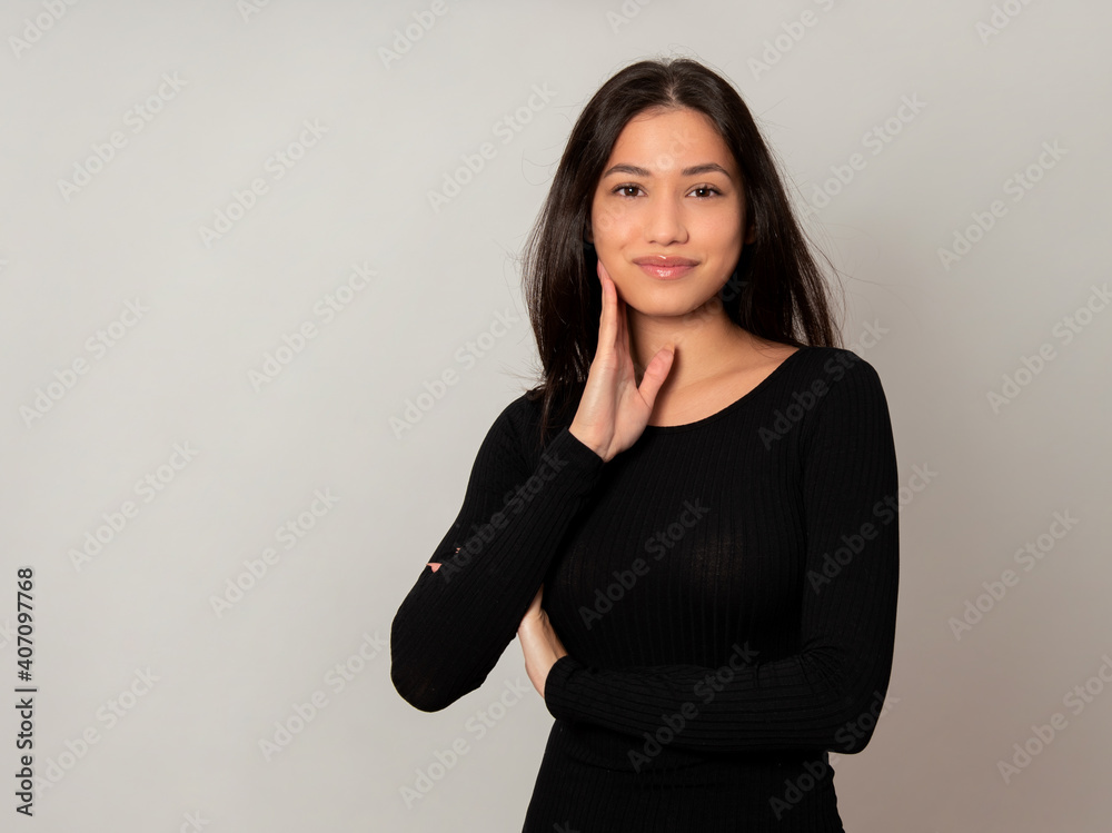 Beautiful young woman with long black hair posing in dress on grey ...