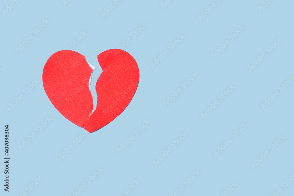 Close up red paper broken heart on blue background. Valentine's Day and depression concept