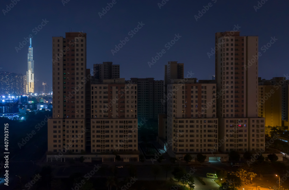 Night view of massive apartment development that is complete but mostly empty. It is dark deserted, eerie and mysterious in the dark night sky. It has been affected by the Covid pandemic. Landmark 