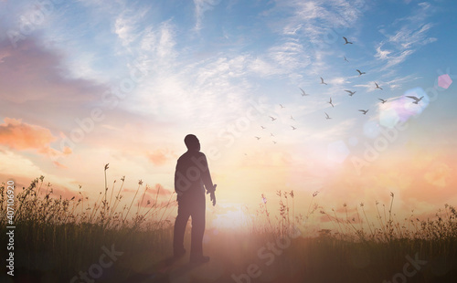 World mental health day concept: Silhouette of human standing to worship God in meadow autumn sunset background