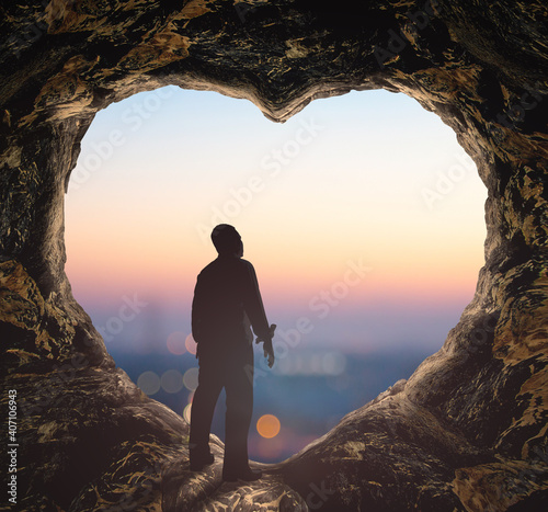 Worship God concept: Silhouette human standing on cave of heart against blurred mountain sunrise background