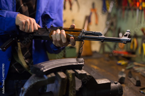 Closeup of Kalashnikov assault rifle in hands of gunsmith. Professional firearms maintenance concept photo