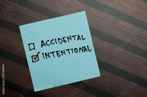 Accidental and Intentional write on sticky notes and supported by additional services write on a sticky notes isolated on Wooden Table. photo