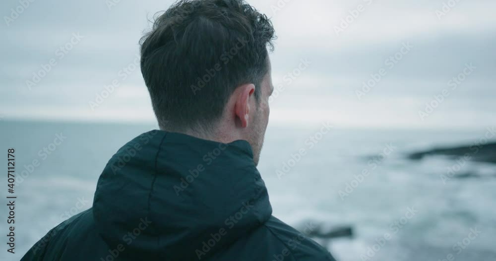 Caucasian man standing at the shore and looking into the distance