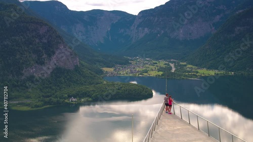 TRACKING ZOOM IN, An athletic woman and man look at the dramatic view, Hallstatt photo