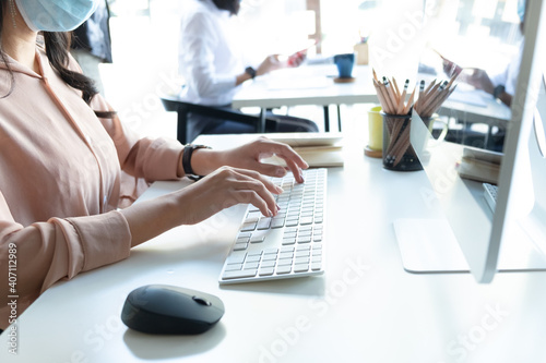 Cropped shot of woman hands typing on laptop keyboard while sitting at the table in office, copy space. photo