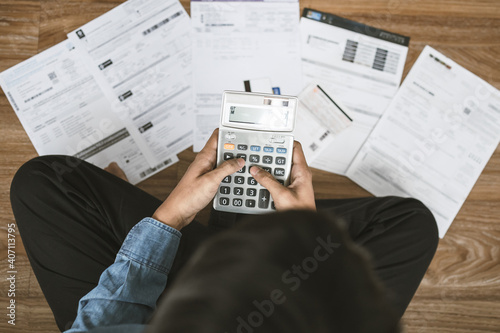 Top view man sitting on the floor stressed and confused by calculate expense from invoice or bill, have no money to pay thinking of taking the house to mortgage causing debt, bankruptcy concept. photo