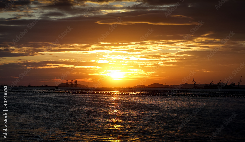 Sunset sky with silhouette of commercial dock and island
