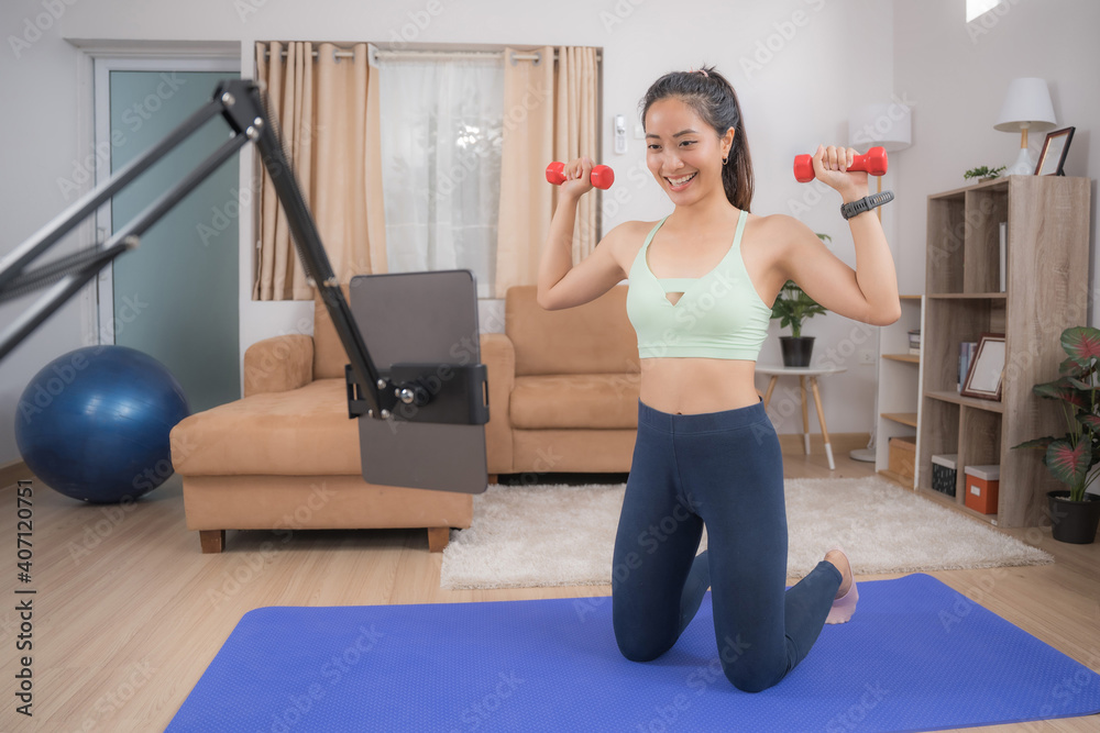 Fototapeta premium Asian woman exercising at home, she is watching online tutor.