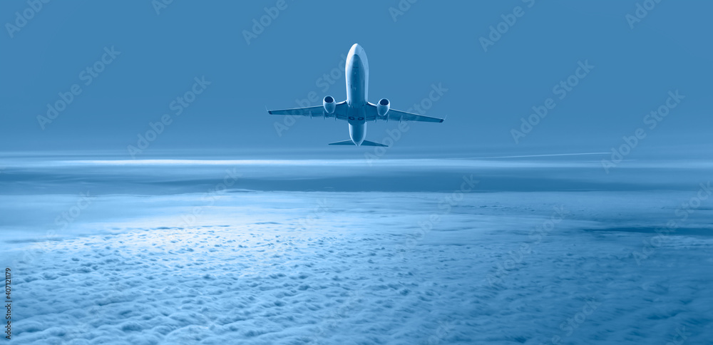 Fototapeta premium White passenger airplane over the clouds - Travel by air transport
