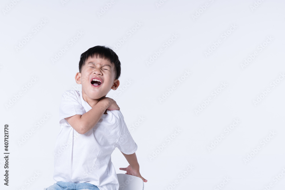 Asian boy touching his shoulder with hurt expression Asian boy touching his shoulder with hurt expression