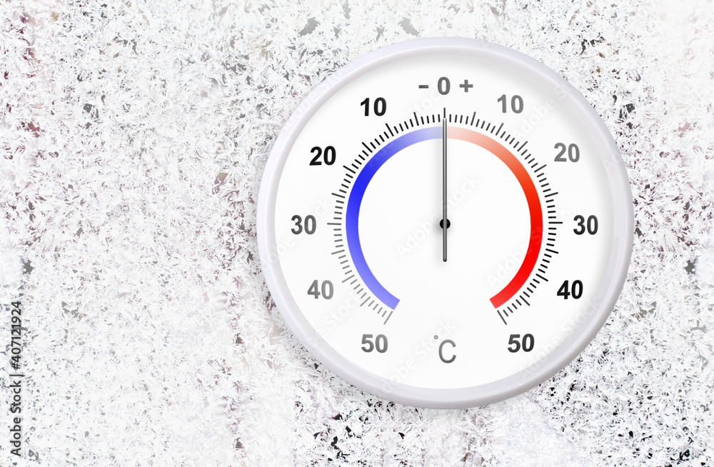 Naklejka premium Celsius scale thermometer on a frozen window shows zero degrees