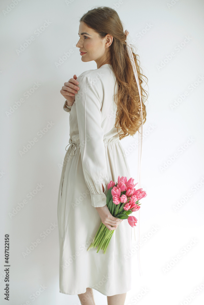 Attractive young woman in natural fabric dress holding a bouquet of tulips, isolated on white background. High quality photo. Attractive young woman in natural fabric dress holding a bouquet of tulips, isolated on white background. High quality photo.