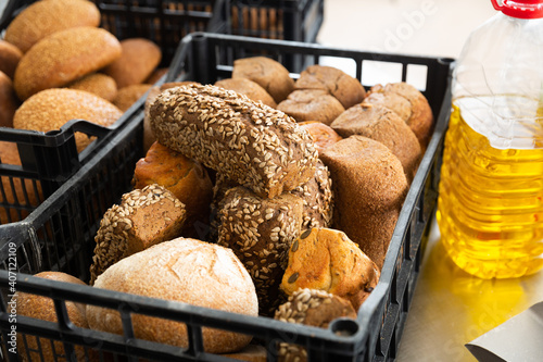 Freshly baked hot bread in plastic crate on table with ingredients, industrial bread production