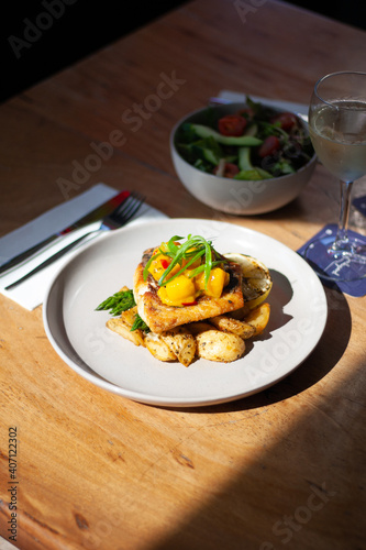 Fish Dish with Mango salsa on table with fresh salad and wine glass in sunlight. Great on it's own, for social media or for a poster.